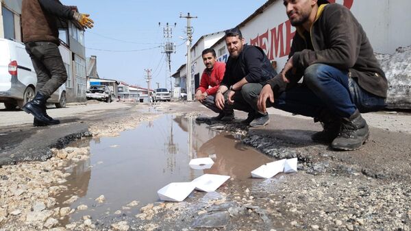 Yol sorununa dikkat çekmek isteyen esnaf, kağıttan kayık yapıp su dolu çukurlarda yüzdürdü - Sputnik Türkiye