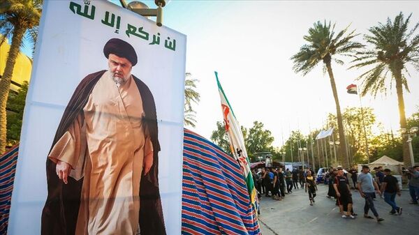 Taraftarlarının başkent Bağdat'taki hükümet binalarının bulunduğu Yeşil Bölge'de protesto düzenlediği Iraklı Şii lider Mukteda es Sadr'ın posterinin yanından geçenler - Sputnik Türkiye