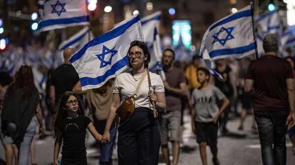 İsrailliler, Başbakan Benyamin Netanyahu öncülüğündeki koalisyon hükümetinin yargının yetkililerini sınırlayan düzenlemesine ve sağ politikalarına yönelik protestolarına devam ediyor. Tel Aviv'de binlerce protestocu, ellerinde İsrail bayraklarıyla sık sık demokrasi sloganları atarak koalisyon hükümetindeki aşırı sağcı politikacıları eleştiren dövizler taşıdı.  - Sputnik Türkiye