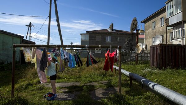Yujno-Kurilsk’in merkezinde bir kadın çamaşır asarken. - Sputnik Türkiye