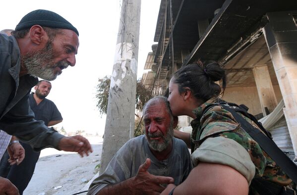 Evlerinden tahliye edilen Menbiçlileri teselli eden Demokratik Suriye Güçleri askeri. - Sputnik Türkiye