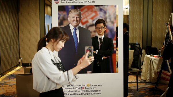 Güney Kore'nin başkenti Seul'deki bir otelde genç bir kadın Trump'ın fotoğrafı ile kendi resmini çekiyor. - Sputnik Türkiye