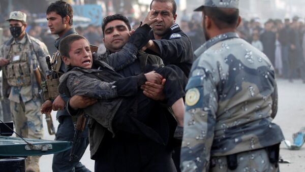 Afgan polisi Celalabad'daki bir bombalı saldırıda yaralanan çocuğu taşıyor - Sputnik Türkiye