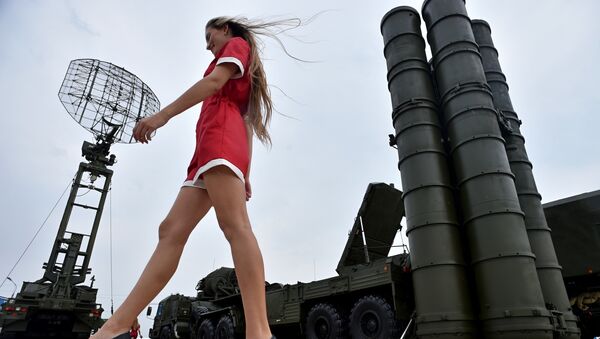 A woman walks near Russia's air defence system S-400 Triumf launch vehicles at the military exhibition - Sputnik Türkiye