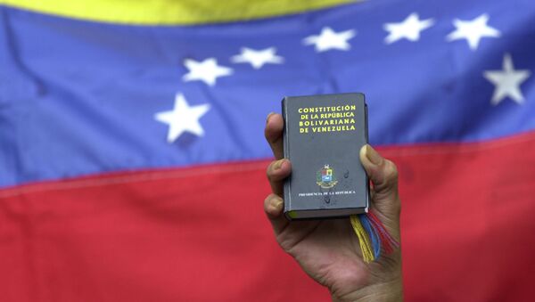 A demonstrator holds up a miniature copy of Venezuela's constitution in front of the nation's flag at a government rally in Caracas, Venezuela, Tuesday, April 13, 2004. - Sputnik Türkiye