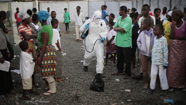 In this file photo daetd Tuesday, Sept. 30, 2014, a medical worker sprays people being discharged from the Island Clinic Ebola treatment center in Monrovia, Liberia - Sputnik Türkiye
