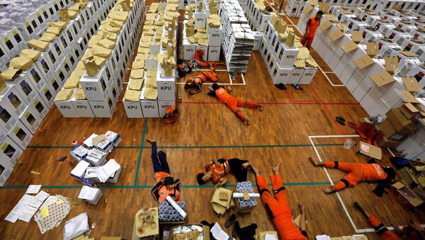 Endonezya'daki dünyanın en büyük tek günlük seçimi öncesinde, sandık materyallerini hazırlayan işçiler başkent Jakarta'da mola sırasında dinleniyor. - Sputnik Türkiye