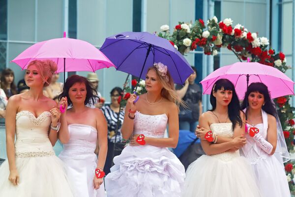 Gelin Yarışları’nın başlamasını şemsiyeleriyle bekleyen kadınlar. - Sputnik Türkiye